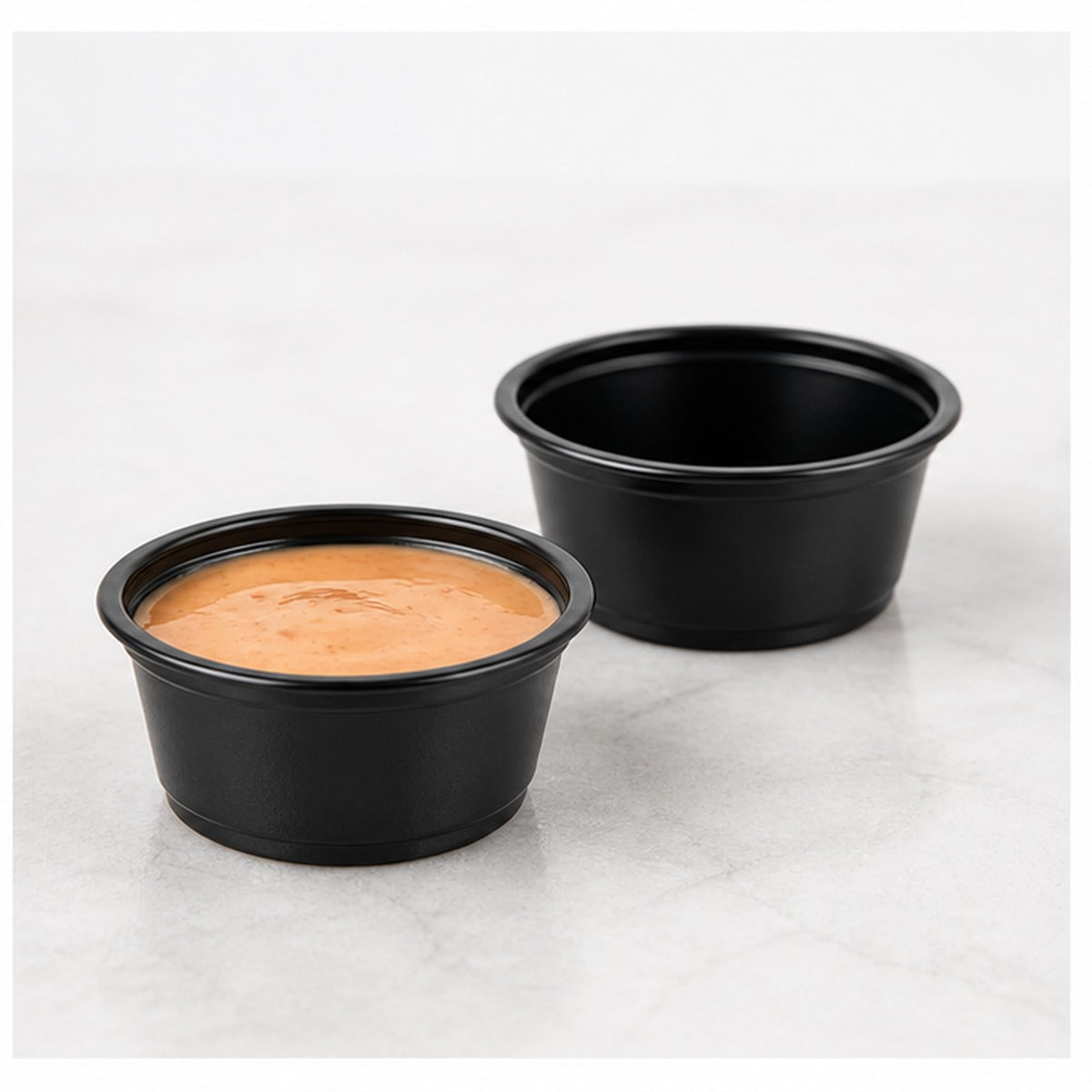 1.5 oz black plastic portion cup filled with sauce - 2,500/Case