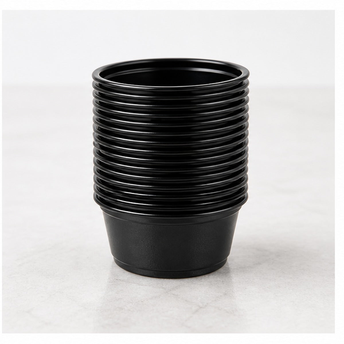 Stack of 1.5 oz black plastic portion cups - 2,500/Case